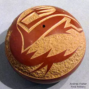 A sgraffito avanyu design on a red seed pot