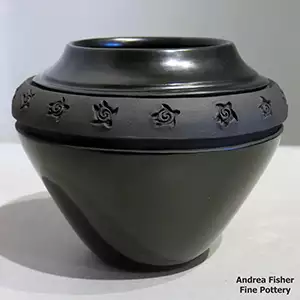Geometric designs carved into the black matte band around the shoulder of a black jar