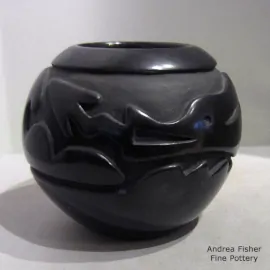 An avanyu design carved around the outside of a black bowl
