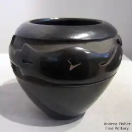 An avanyu design carved into a glossy black jar