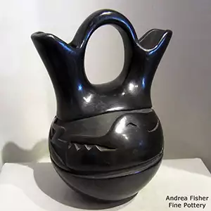 A black wedding vase with an avanyu design carbed around the body