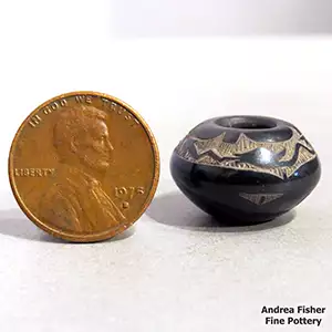 Miniature black jar with a sgraffito avanyu and geometric design