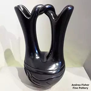 An avanyu design carbed around the shoulder of a black wedding vase