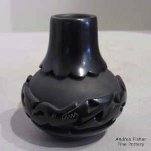 An avanyu and geometric design carved into a miniature black jar