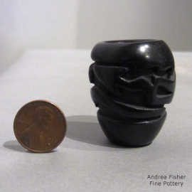 an avanyu designed carved into a miniature black jar