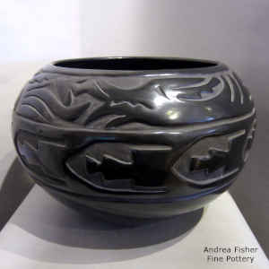 An avanyu and geometric design carved around a black jar