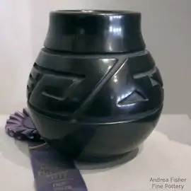 A stylized avanyu design carved into a black jar