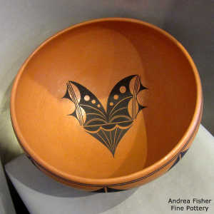 Butterfly design inside and geometric design outside on a golden micaceous bowl