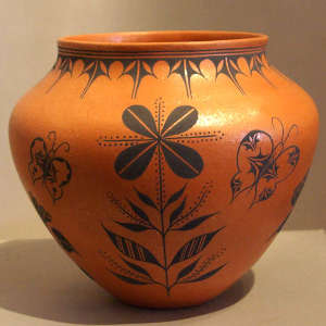 Butterfly, floral and geometric design on an orange micaeous pot