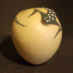 Lizard on top of a buff-colored, egg-shaped seed pot